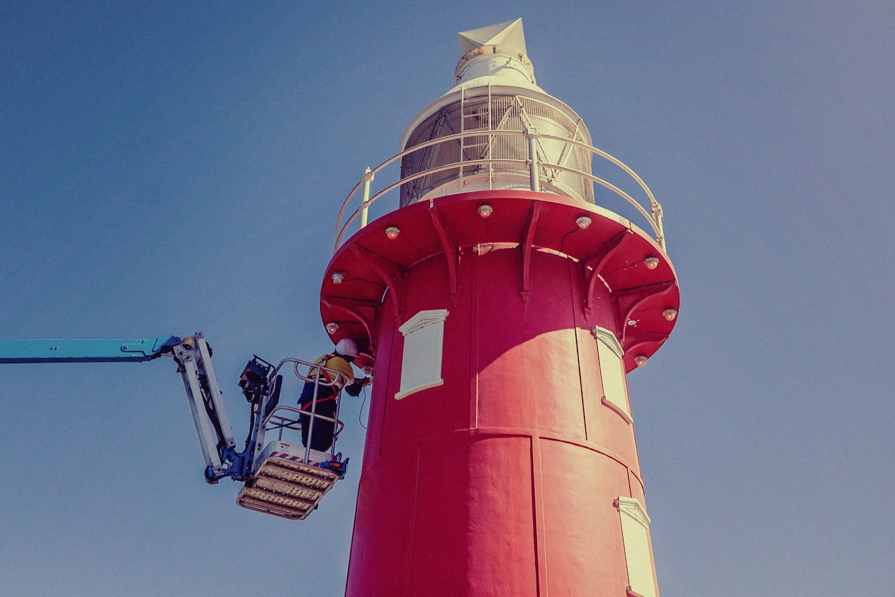 Technicians maintaining a coastal aid to navigation from an elevated work platform